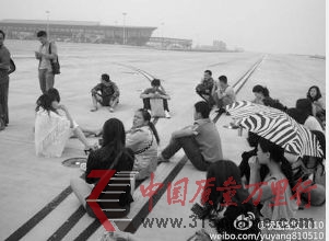 網(wǎng)友@極品寶貝2010在微博上貼出乘客圍坐機(jī)場跑道的照片